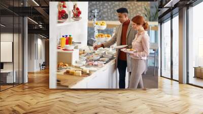 afro-american male talking with caucasian female at lunch break, choosing food from a buffet, smiling Wall mural