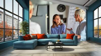 An older business woman asks young female colleague a question during a presentation at workplace. Business, office, job Wall mural