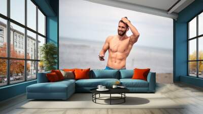 Attractive man walking on the beach; Hot guy concept Wall mural