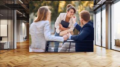 businessman feeding young female colleague outdoor, having fun Wall mural