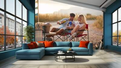 Couple enjoying summertime camping with camper rv in nature, sitting and pouring a glass of wine. Fun, travel, togetherness, lifestyle, love concept. Wall mural