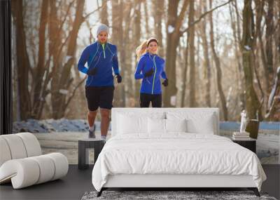 Couple in winter running together in nature Wall mural