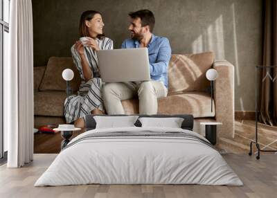 couple spending time at home, sitting on bed with laptop.. Wall mural