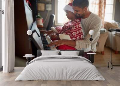 father with child girl on Christmas morning play music on piano. Wall mural