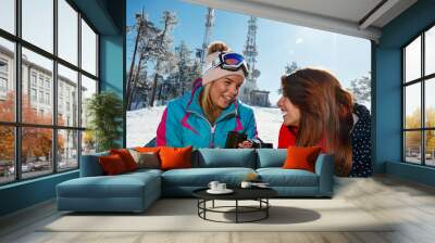 female friends enjoying hot drink in cafe at ski resort Wall mural