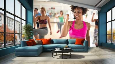 Female instructor with headset in fitness class Wall mural