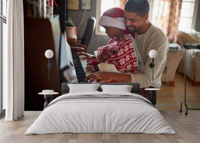 girl playing piano on Christmas Day..Girl and father  together play music at piano. Wall mural