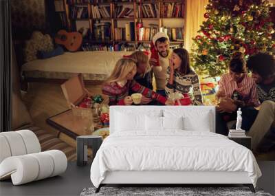 group of friends laughing and sharing Christmas gifts.. Wall mural