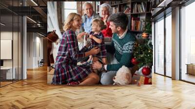 Happy family sitting next to a Christmas tree Wall mural