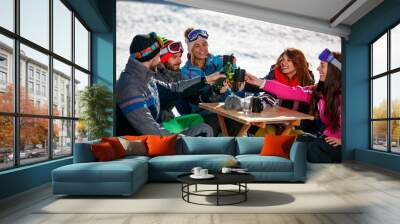 happy friends cheering with drink after skiing day in cafe at ski resort Wall mural