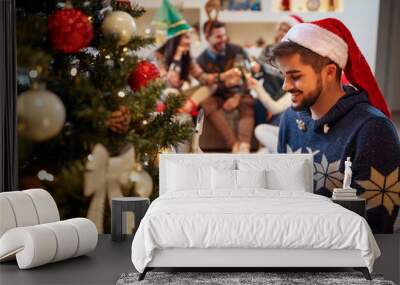 happy man in Santa's hat with Christmas presents at home. Wall mural