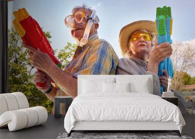 Modern Senior couple have fun playing with  water gun. Wall mural