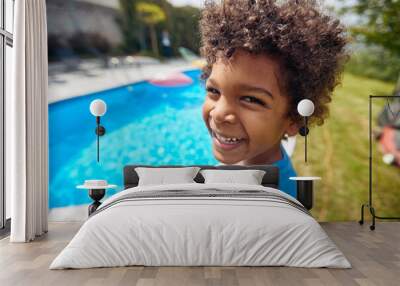 Portrait shot of lovely african american boy standing by the outdoor in ground pool in the backyard, smiling and feeling happy. Wall mural