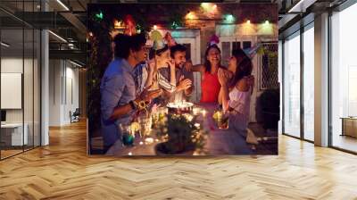 Smiling group of young friends having  birthday party in the club with cake and candles at night.  Party, fun, birthday concept. Wall mural