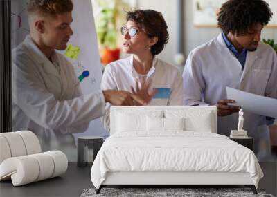 Team of young laboratory technicians discussing test results Wall mural