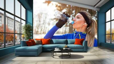 Thirsty female athlete drinking water . Wall mural