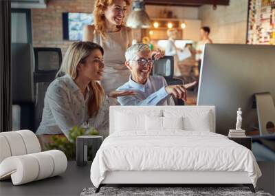 Two younger women colleagues being mentored by senior successful businesswoman Wall mural