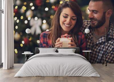 Woman with husband looking at Christmas gift Wall mural