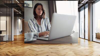 Working home concept – woman works for a computer from a home with a laptop   as a freelancer. Wall mural