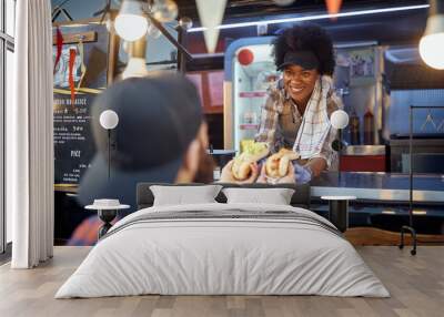 young afro-american employee giving with smile sandwiches through a fast food window to a satisfied customer Wall mural