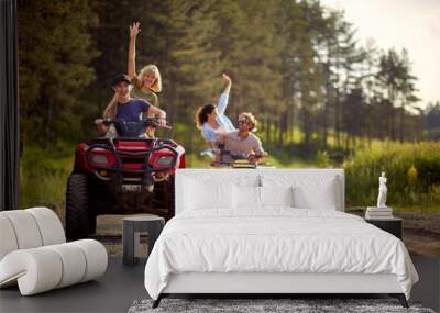 Young friends ride quads on a road in the nature. Wall mural