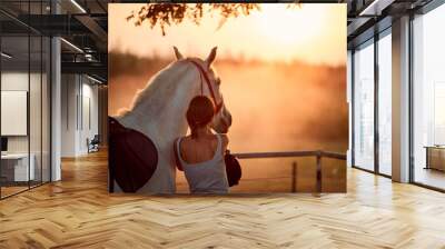 Young rider girl with her horse at sunset. Wall mural