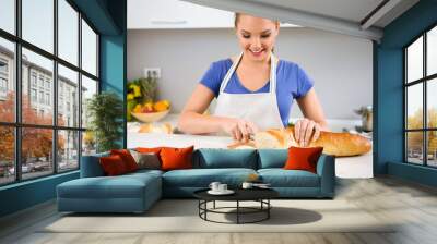 young woman in kitchen cutting bread Wall mural