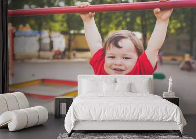 portrait of cute little boy in red t-shirt excitedly playing and smiling on playground. concept of happy healthy child Wall mural