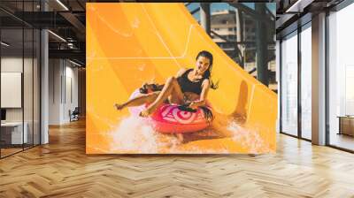 pretty smiling woman on the rubber ring having fun on the orange water slide in the aqua park. Summer Vacation. Weekend on resort Wall mural