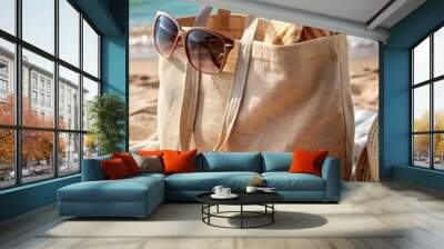 Plain canvas tote bag on a sandy beach, blank and ready for summer designs, with a beach towel and sunglasses beside it Wall mural