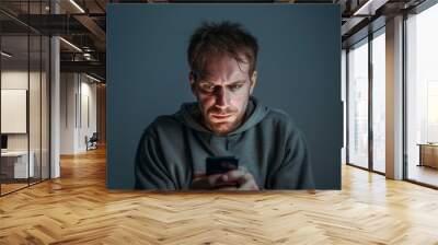 A stressed white man nervously looks at his cellphone or mobile in horror, a victim of revenge porn, cyberstalking, fraud or blackmail, square format Wall mural