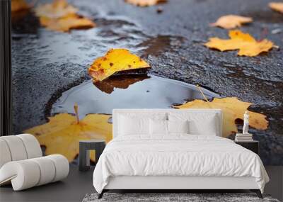 Autumn breeze carries fallen golden leaves over rain puddles on city pavements, showcasing the beauty of seasonal changes and urban landscapes. Wall mural