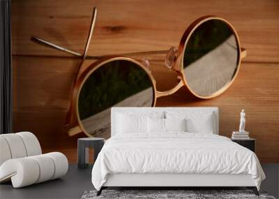 Mirror round sunglasses with a gold frame lie on a wooden surface Wall mural