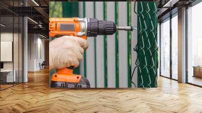 Work with an electric drill to strengthen the netting of the chain-link on a metal fence. Wall mural