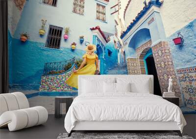 Colorful traveling by Morocco. Young woman in yellow dress walking in  medina of  blue city Chefchaouen. Wall mural