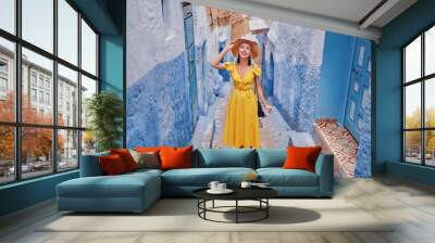 Colorful traveling by Morocco. Young woman in yellow dress walking in  medina of  blue city Chefchaouen. Wall mural