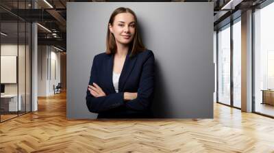 Confidence and charisma. Young business woman in suit looking at camera. Grey background. Wall mural