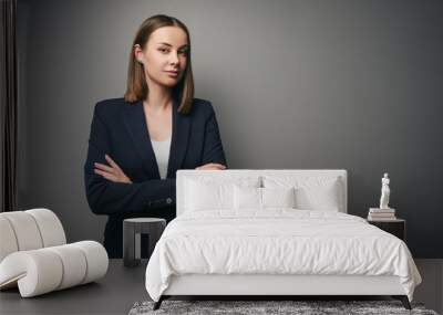 Confident young business woman in suit looking at camera. Grey background with copy space. Wall mural