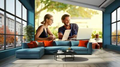 Coworking and freelance concept. Young  bearded man  and young woman working together on laptop computer while sitting on cafe terrace. Wall mural