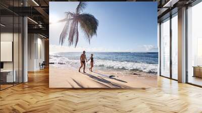 Honey moon on the sea shore. Back view of loving couple walking together on beautiful tropical white sand beach. Wall mural