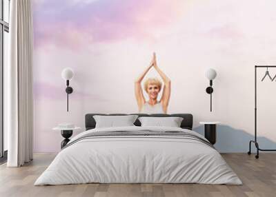 Senior woman doing yoga exercises with mountain sunset on the background Wall mural