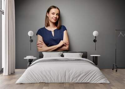 Studio portrait of young business woman looking at camera against grey wall. Wall mural