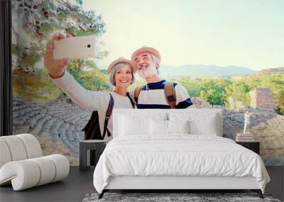 Tourism and technology. Traveling senior couple taking selfie together against ancient sightseeing background. Wall mural