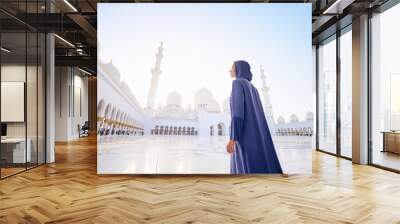 Traveling by Unated Arabic Emirates. Woman in traditional abaya standing in the Sheikh Zayed Grand Mosque, famous Abu Dhabi sightseeing. Wall mural