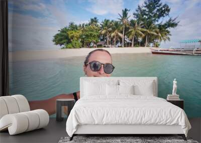 Traveling in Philippines. Happy young woman taking selfie while bathing near small island with white sand tropical beach. Wall mural