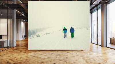 Two friends walking together by snowy field. Wall mural