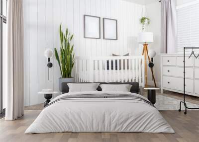 A modern farmhouse baby nursery bedroom with blank mock-up picture frames on the wall.  Wall mural