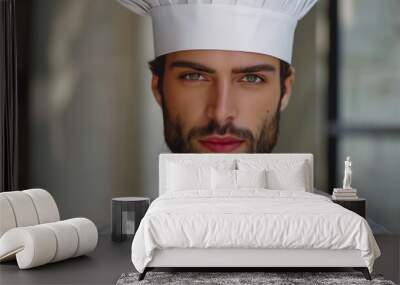 Portrait of a handsome male chef wearing a traditional white chef's hat and uniform, standing in a professional kitchen environment with a focused and confident expression Wall mural