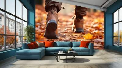 A close-up shot of hiking boots walking on a trail covered in fallen autumn leaves Wall mural