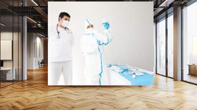 Doctor in mask and protective costume using dropper in hospital Wall mural